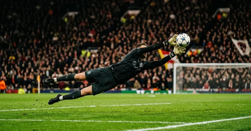 Soccer goalkeeper at full stretch making a diving save under stadium floodlights