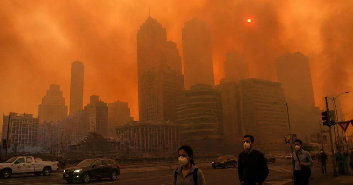 City skyline obscured by thick wildfire smoke haze with an orange-brown sky and dim red sun