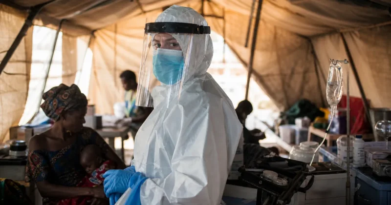 Medical humanitarian worker in protective hazmat gear at a makeshift field clinic