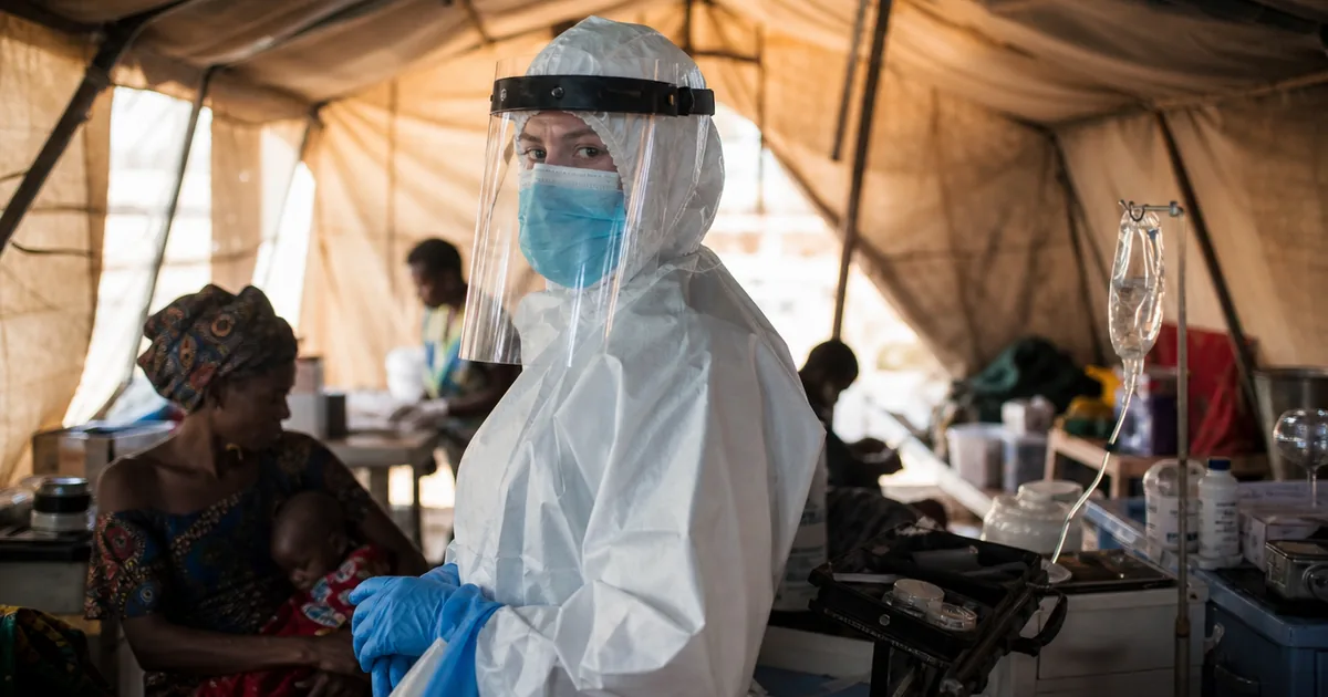 Medical humanitarian worker in protective hazmat gear at a makeshift field clinic