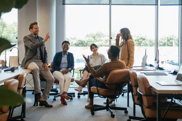 Colleagues talking and laughing during an informal meeting in a bright open-plan office