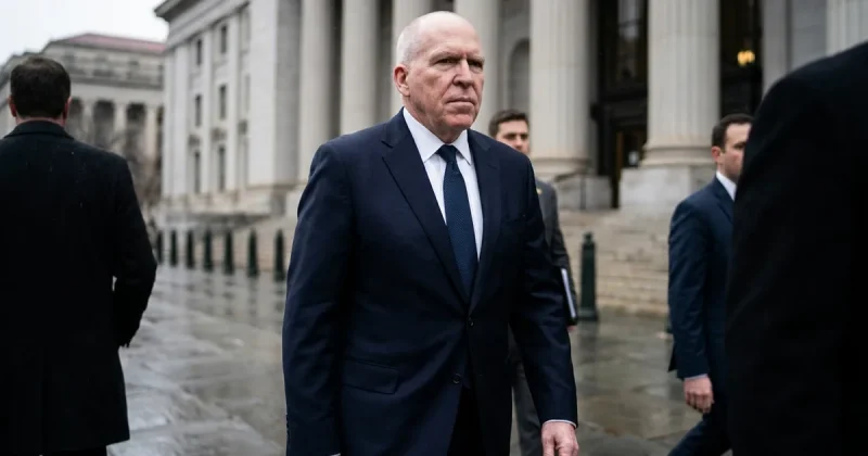 Former CIA Director John Brennan in a dark suit walking past the columned facade of a Washington DC federal courthouse