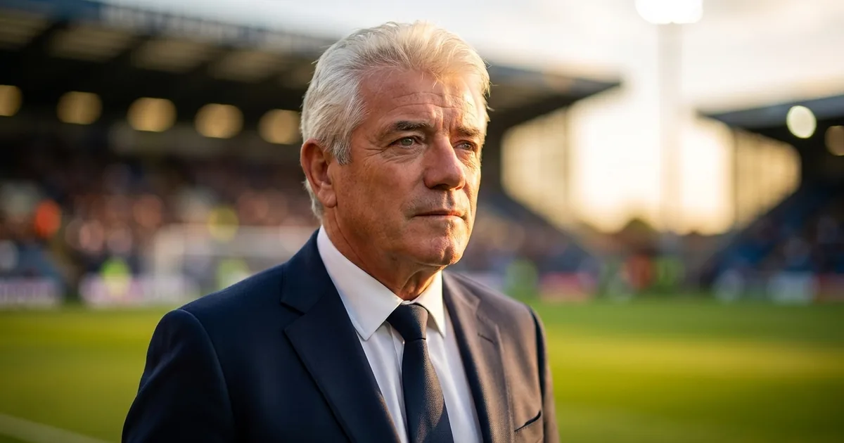 Kevin Keegan in a dark suit at a football stadium during golden hour