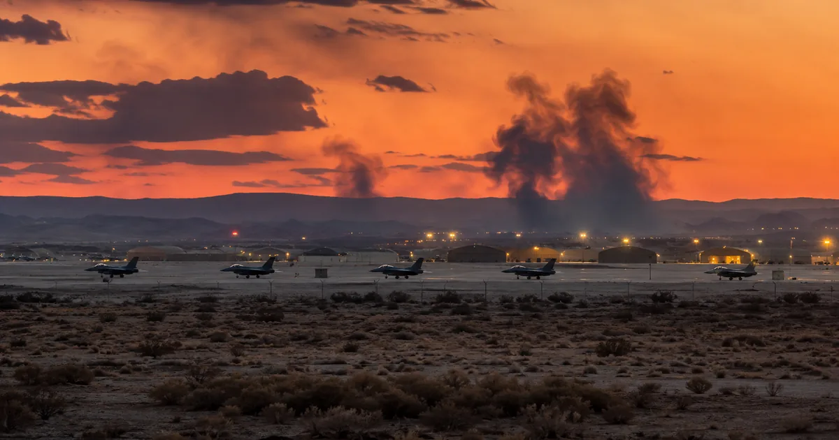 Smoke rising from Muwaffaq Salti Air Base in Jordan at dusk with US military fighter jets on the tarmac