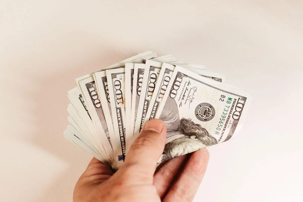 Hand holding a fan of one hundred dollar bills