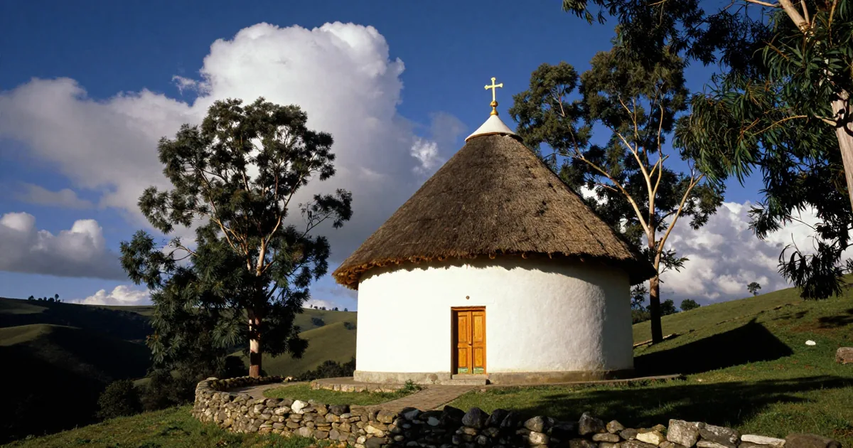 Illustrative image of a round whitewashed Ethiopian Orthodox church with a thatched roof and a gold cross on a green highland hillside under a deep blue sky