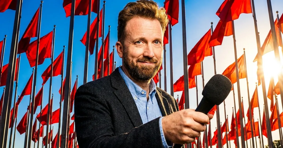 Comedian Jordan Klepper smiling at the camera with a microphone, surrounded by tall red flags against a blue sky