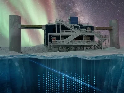 The IceCube Lab building at the South Pole under green aurora, with a cutaway of the ice below showing strings of glowing light sensors