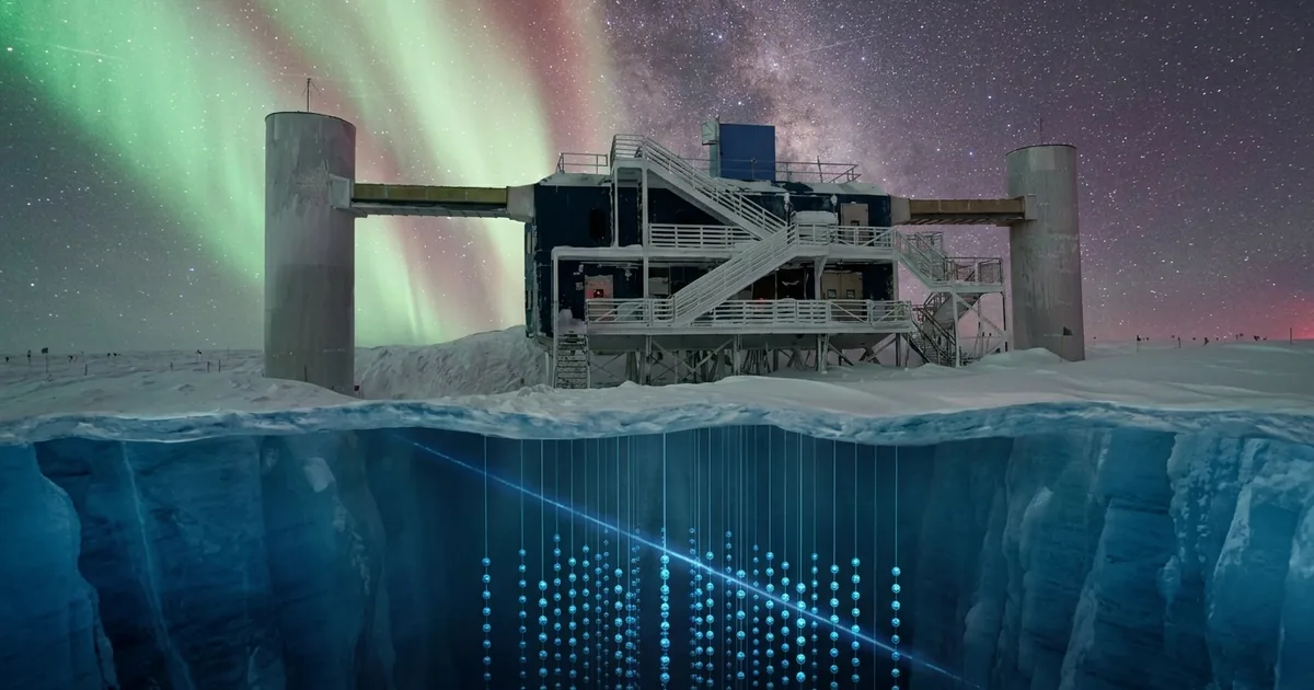 The IceCube Lab building at the South Pole under green aurora, with a cutaway of the ice below showing strings of glowing light sensors
