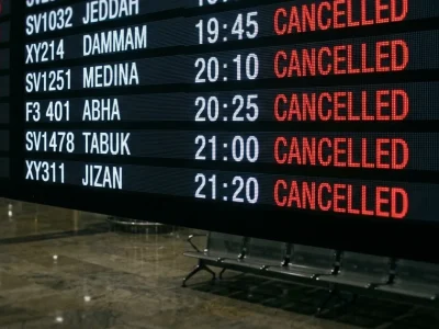 Illustration of an airport departures board in a darkened terminal with flights to Jeddah, Dammam, Medina, Abha, Tabuk and Jizan all marked cancelled in red
