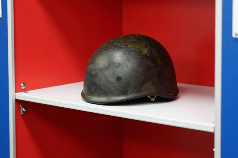 A military combat helmet on the shelf of a red and blue voting booth