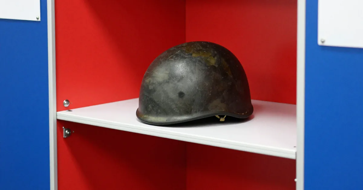 A military combat helmet on the shelf of a red and blue voting booth